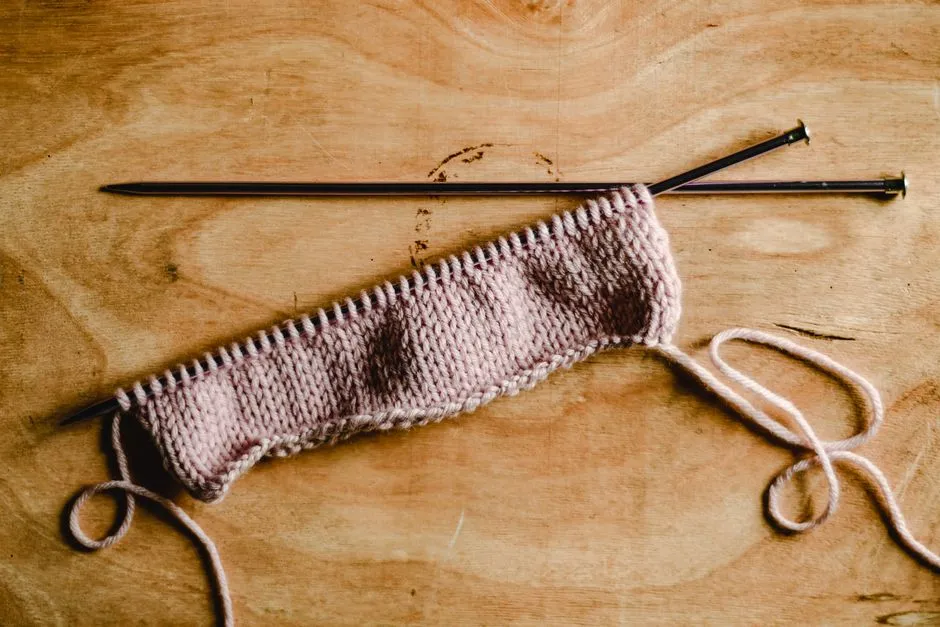 A pair of knitting needles resting on a wooden surface