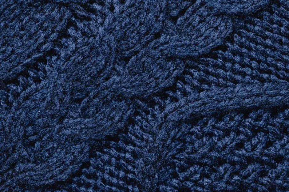 Close-up of a blue cable-knit fabric showing the crossed-stitch texture
